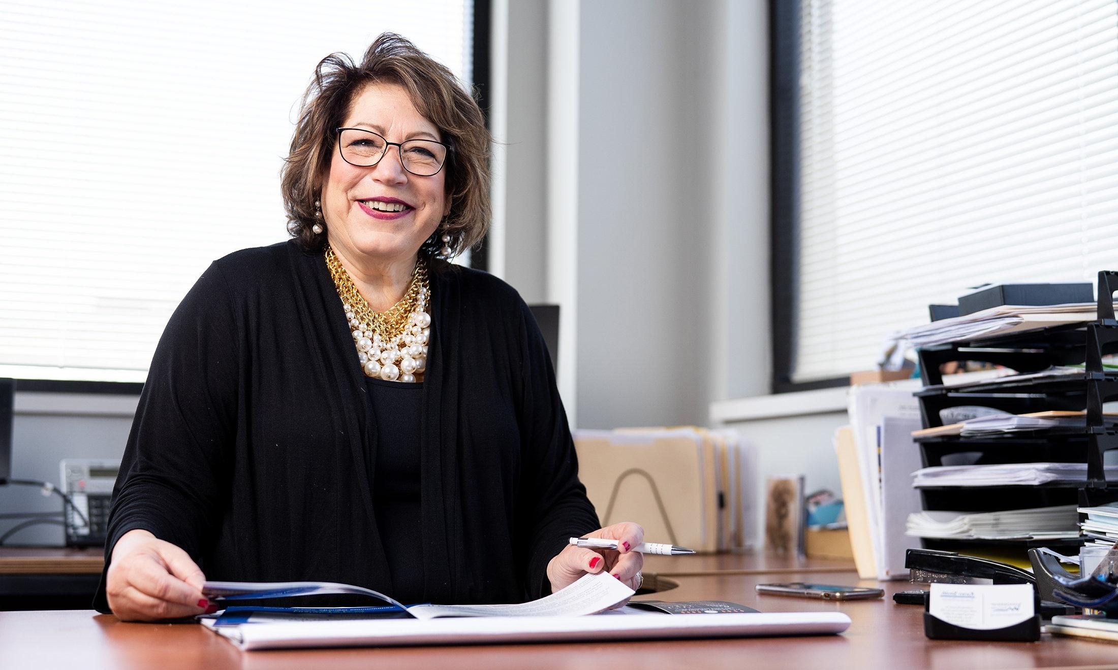 A woman smiling at her desk.